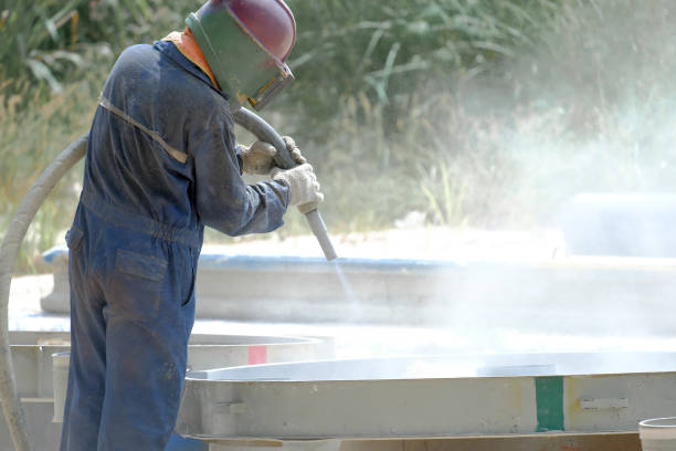 Worker is remove paint by air pressure sand blasting in a field, And wear a suit for protection